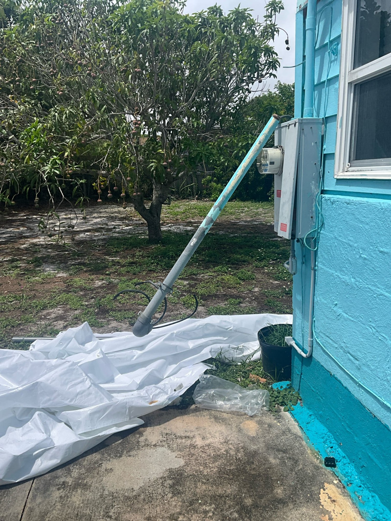 Broken conduit with white protective wrap and meter base visible on exterior of structure.