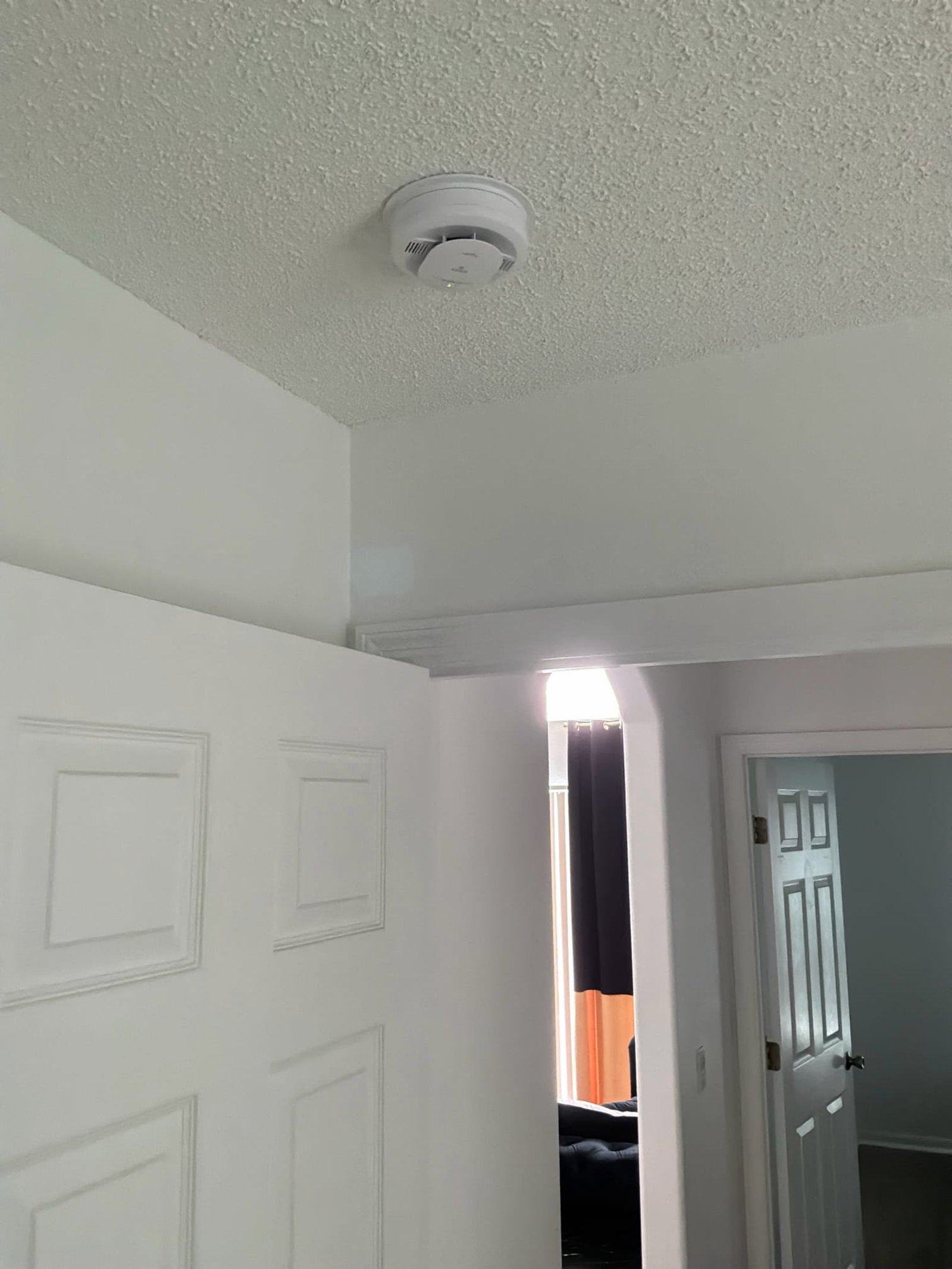 Finished interconnected smoke detector mounted on the hallway ceiling