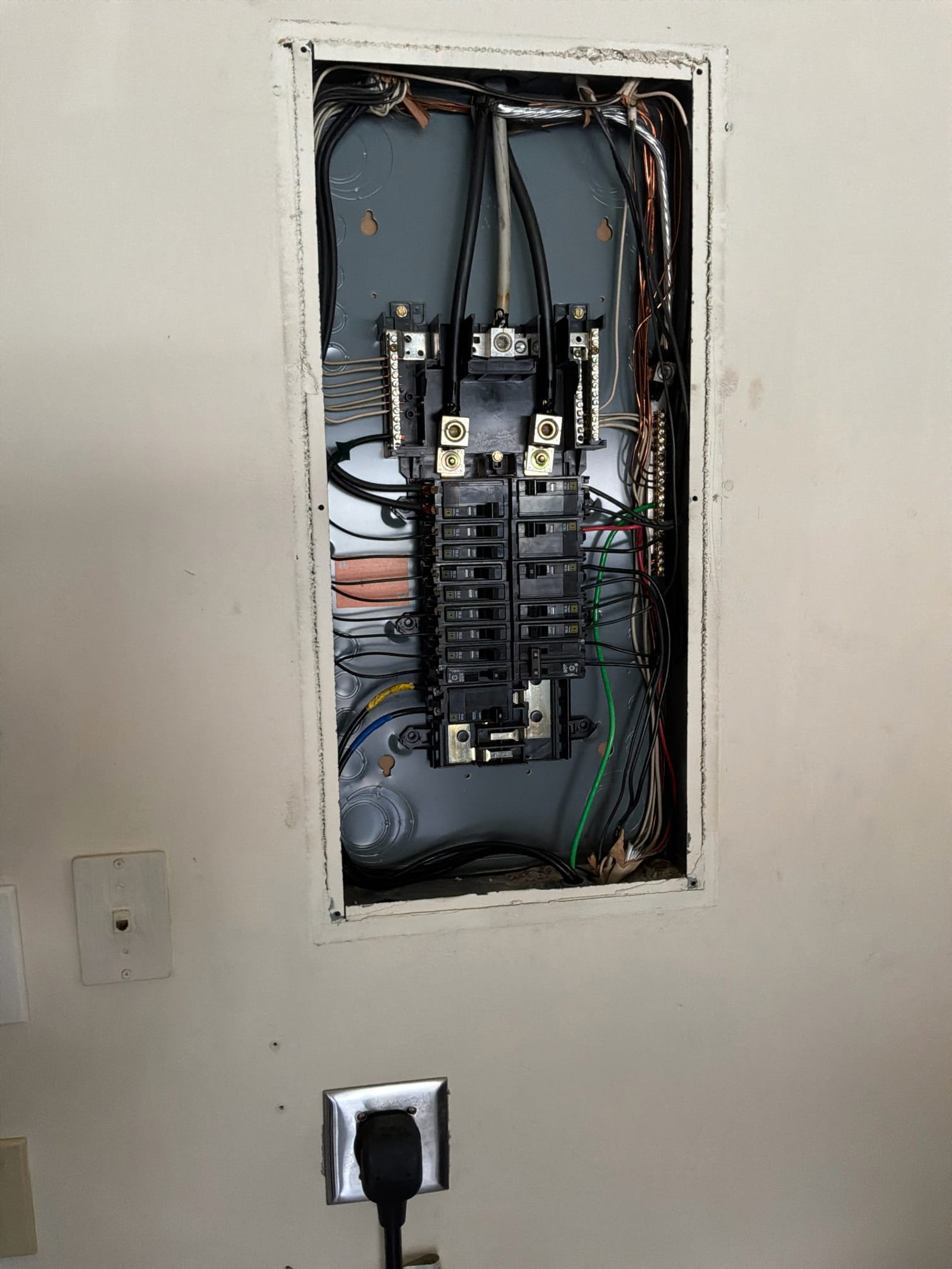 Panel interior showing double-pole breakers, single-pole breakers, and multiple wire connections with organized conductor runs.