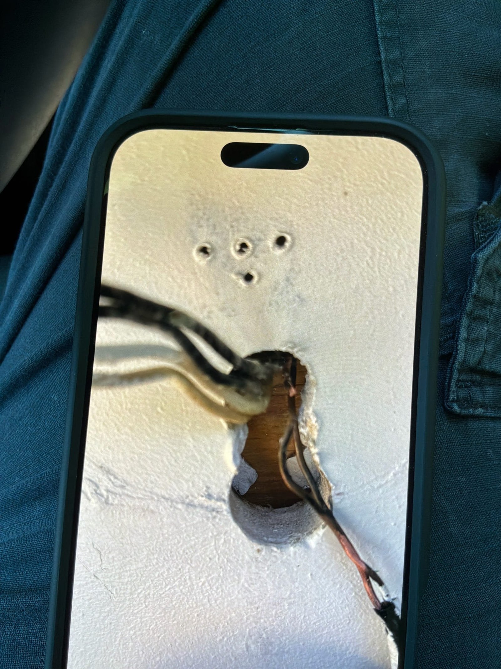 Phone close-up of weathered exterior fixture wiring showing oxidation and corrosion on conductors.