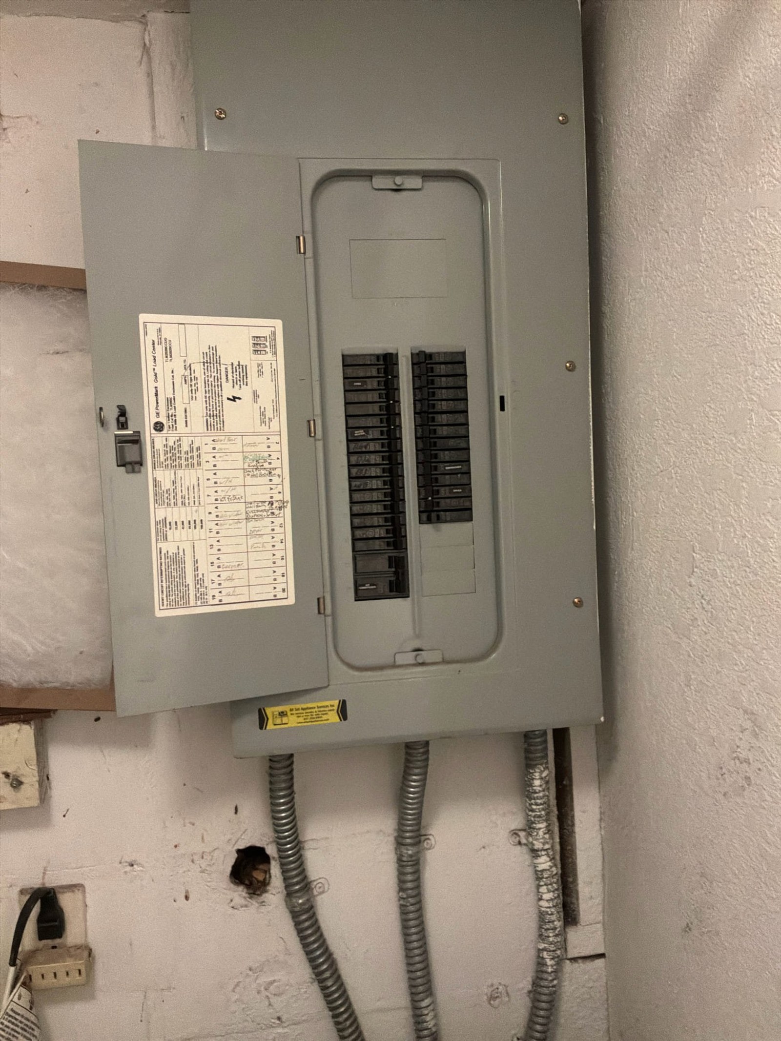 Main electrical panel with breaker interior showing two-pole and single-pole breakers and circuit directory.