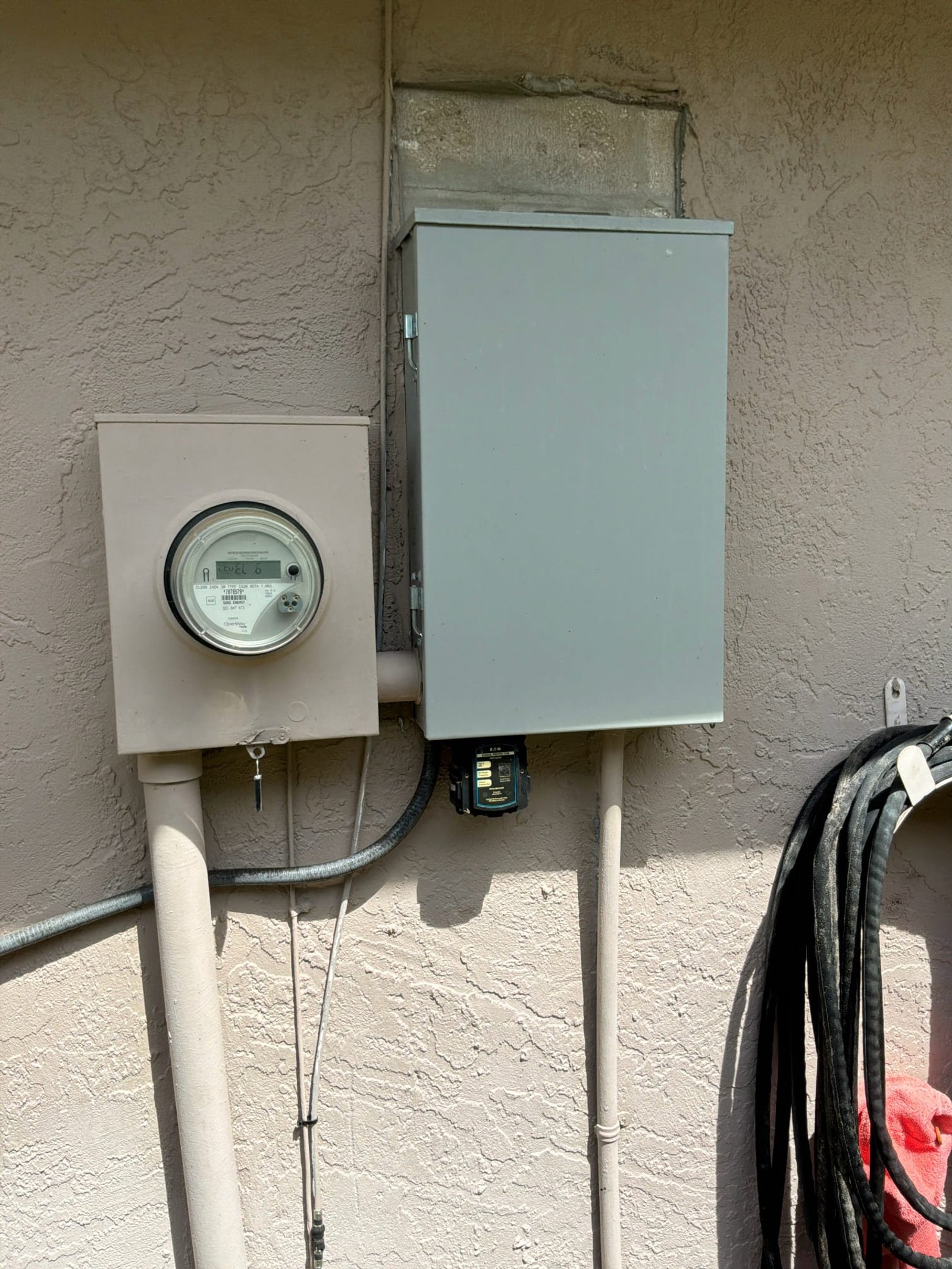 Exterior meter and subpanel enclosure mounted on house wall with digital meter and service disconnect visible.