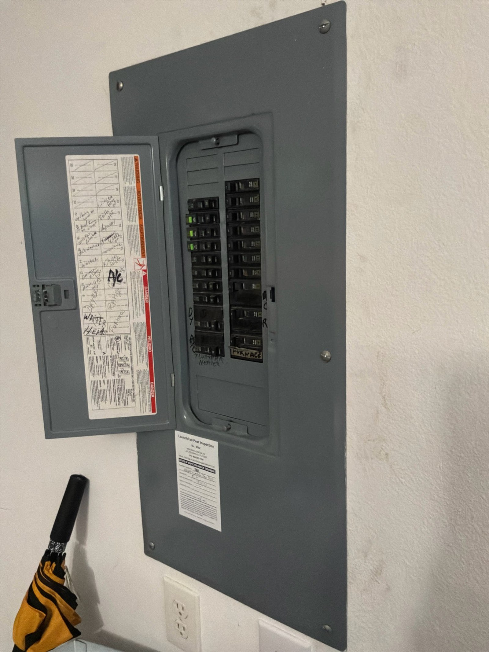 Main electrical panel with open door showing breaker configuration and handwritten annotations on interior cover.