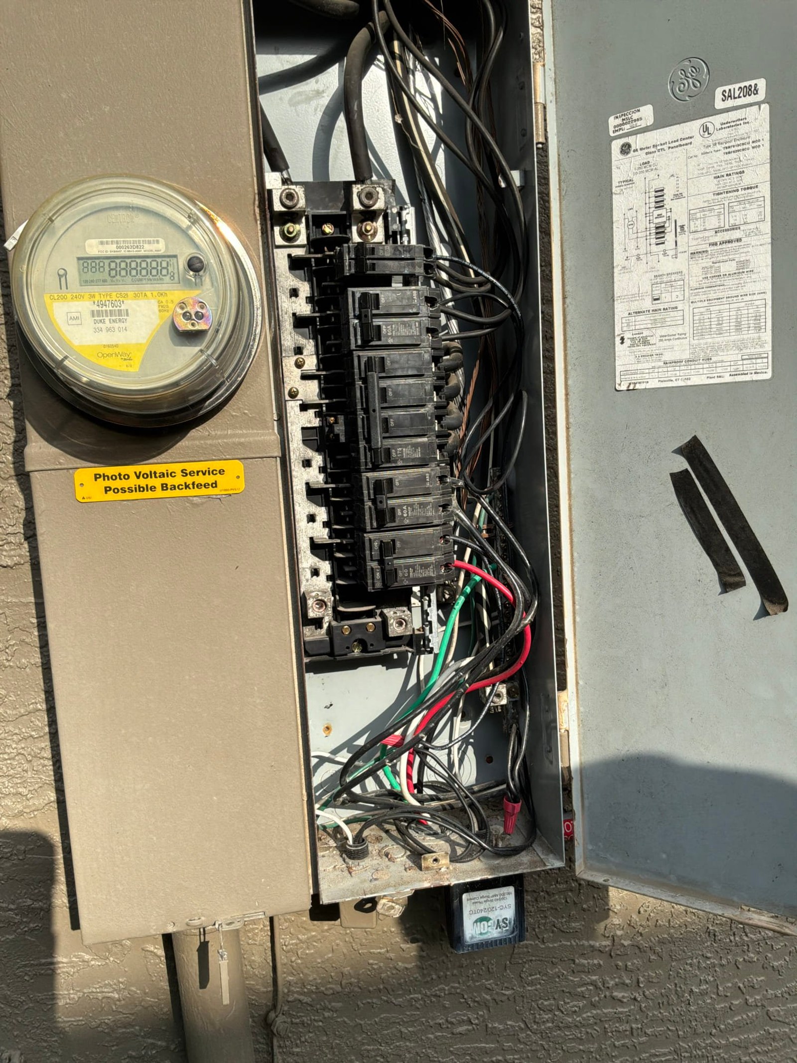 FPE main service panel showing utility meter on left with yellow 'Photo Voltaic Service Possible Backfeed' label, multiple circuit breakers with backstabbed neutrals in center, and schematic diagram on right.
