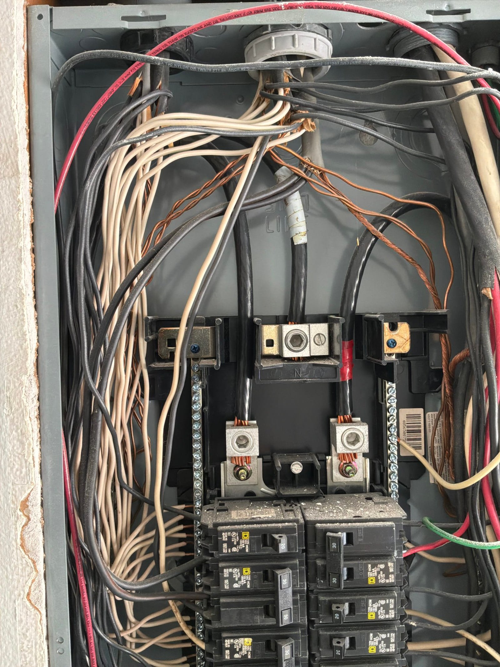 Panel interior showing messy wiring, mixed wire colors, and disorganized circuit configuration.